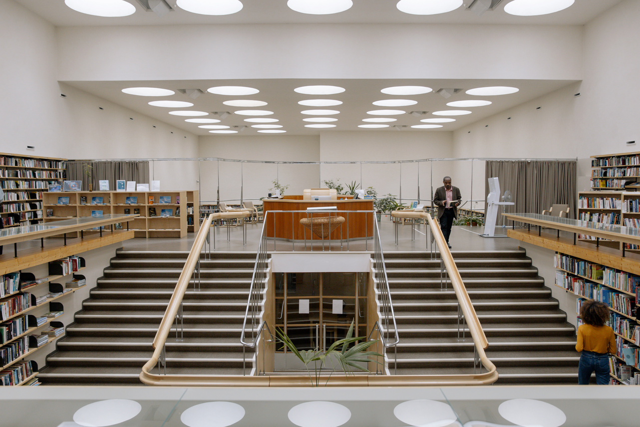 Black man with book near stairs in public library